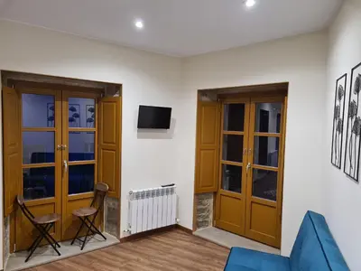 a living room with wooden doors and a tv at Casa da Marquesa Sarria in Sarria