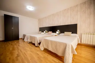 two beds in a room with wooden floors at Noja rooms 1 in O Pedrouzo