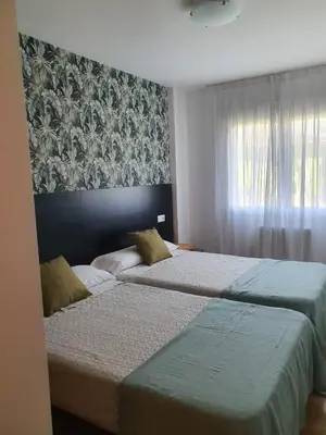 two beds in a bedroom with a wall mural at Noja rooms 1 in O Pedrouzo