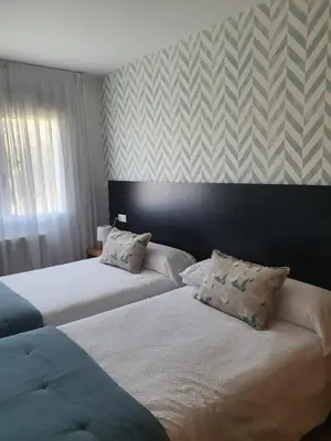 two beds in a hotel room with striped wallpaper at Noja rooms 1 in O Pedrouzo