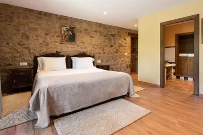 a bedroom with a large bed and a stone wall at Pazo de Moreda in Sober