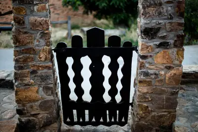 a black fence on the side of a brick wall at Lares · Cabañas Rurales in Las Médulas
