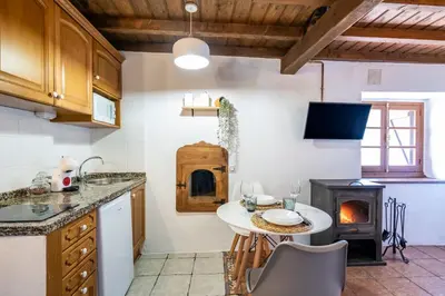 a kitchen with a table and a wood stove at Apartamentos Rurales La Laguna Somiedo in Valle de Lago