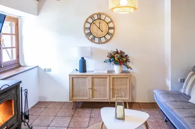 a living room with a couch and a clock on the wall at Apartamentos Rurales La Laguna Somiedo in Valle de Lago