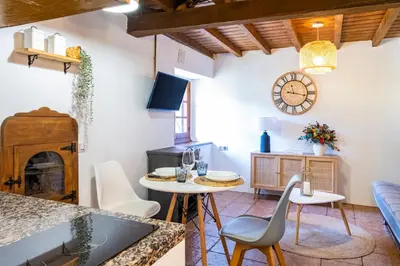a living room with a table and chairs and a clock at Apartamentos Rurales La Laguna Somiedo in Valle de Lago