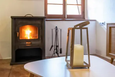 a table with a candle in front of a stove at Apartamentos Rurales La Laguna Somiedo in Valle de Lago