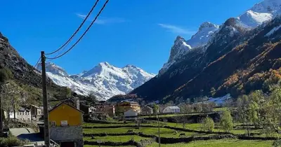 a village in a valley with mountains in the background at Apartamentos Rurales La Laguna Somiedo in Valle de Lago