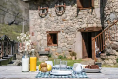 a table with a plate of food and drinks on it at Apartamentos Rurales La Laguna Somiedo in Valle de Lago
