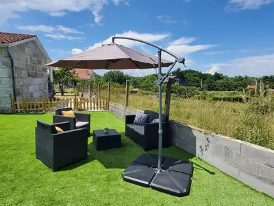a patio with two chairs and an umbrella on the grass at Villa Peregrina in Ourense
