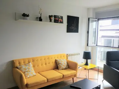 a living room with a yellow couch and a window at Viveiro Centro in Viveiro