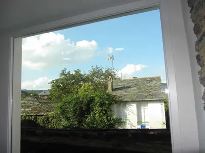 a window with a view of a house and a windmill at Casa Taboada in Sarria
