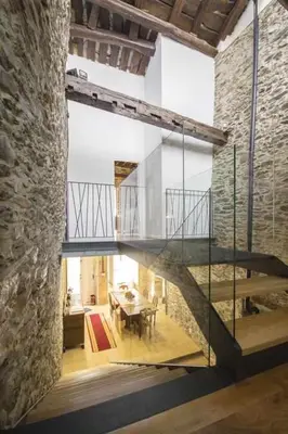 a staircase in a room with a table and a stone wall at Casa Taboada in Sarria