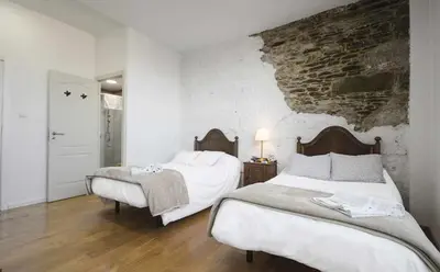 a bedroom with two beds and a brick wall at Casa Taboada in Sarria