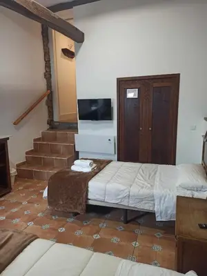 a room with two beds and a tv and stairs at Casa Taboada in Sarria