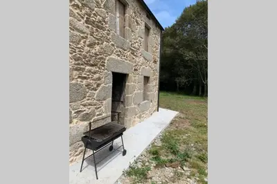 a grill sitting outside of a stone building at Casa Rural en Valadouro Serra do Xistral Lugo En medio de la Naturaleza in Lagoa