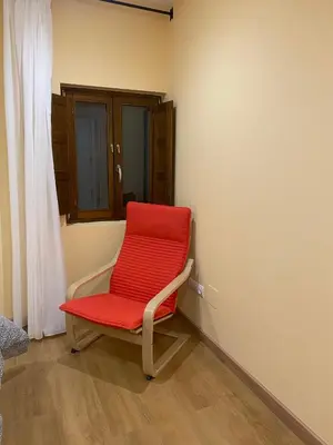 a red chair sitting in the corner of a room at Tu&Mi Villafranca in Villafranca del Bierzo