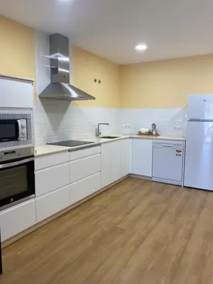 a large kitchen with white cabinets and appliances at Tu&Mi Villafranca in Villafranca del Bierzo