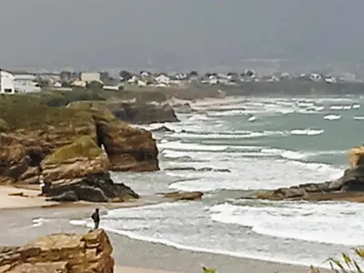 a person standing on a beach near the ocean at Casa o Furco in Foz
