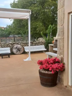 a patio with two benches and a white canopy and flowers at Pensión O Corazón da Ribeira Sacra in La Teijeira