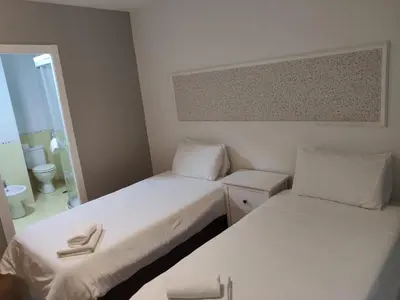 two beds in a small room with a bathroom at Ecorooms SCQ estación in Santiago de Compostela