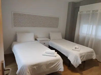 two beds in a room with white sheets and towels at Ecorooms SCQ estación in Santiago de Compostela