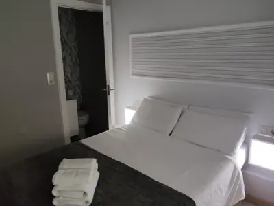 a bedroom with a bed with white sheets and two towels at Ecorooms SCQ estación in Santiago de Compostela