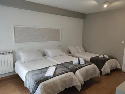 two beds in a room with white walls at Ecorooms SCQ estación in Santiago de Compostela
