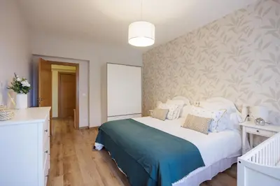 a bedroom with a large white bed with blue sheets at Adeinés Viviendas uso turístico medio in A Estrada
