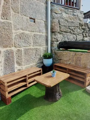 a table and benches sitting next to a stone wall at A Casiña do Xastre in Pontevedra