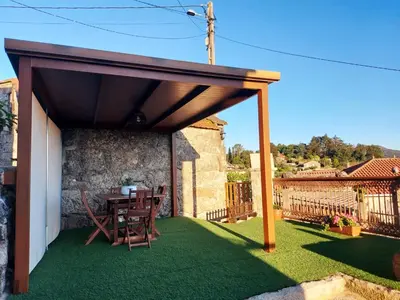 a patio with a wooden pergola and grass at A Casiña do Xastre in Pontevedra