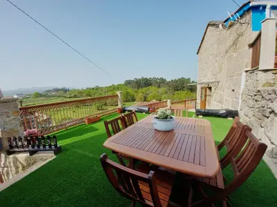 a wooden table and chairs on a green lawn at A Casiña do Xastre in Pontevedra