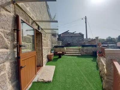 a patio with green grass and a wooden door at A Casiña do Xastre in Pontevedra