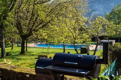 a black barbecue grill in a park with a pool at Villa Ponte Bora in Pontevedra