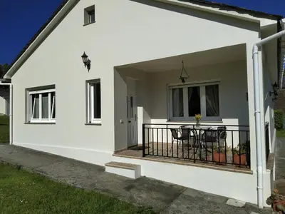 a white house with a balcony with a table at O abeiro de Buscalte in Roupar