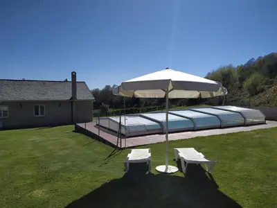 a patio with an umbrella and two white lounge chairs at O abeiro de Buscalte in Roupar