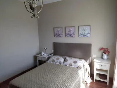 a bedroom with a bed with two night stands and two pictures on the wall at O abeiro de Buscalte in Roupar