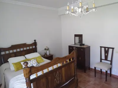 a bedroom with a wooden bed and a chair at O abeiro de Buscalte in Roupar