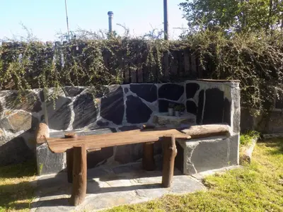 a wooden bench sitting next to a stone wall at Cabaña Bioxana in Molejón