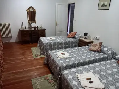 a living room with two beds and a tv at EL BORDON DE LA CASA BATALLON in Sarria