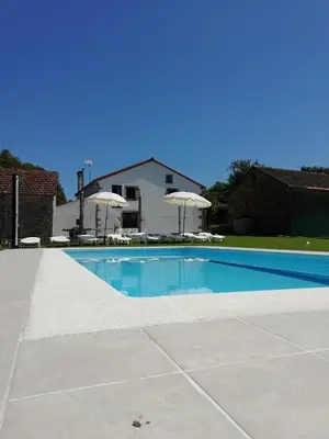 a swimming pool in a yard with umbrellas at BUELIÑA DA CARBALLEIRA in Teo