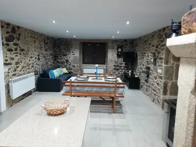 a living room with a table and a stone wall at BUELIÑA DA CARBALLEIRA in Teo