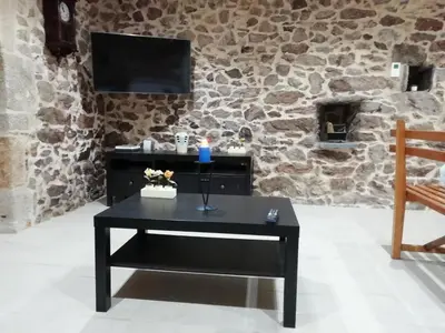a black coffee table in a room with a stone wall at BUELIÑA DA CARBALLEIRA in Teo