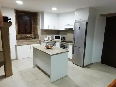 a kitchen with white cabinets and a stainless steel refrigerator at BUELIÑA DA CARBALLEIRA in Teo