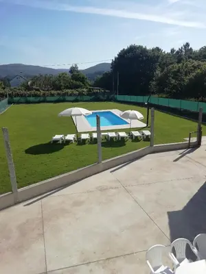 a swimming pool with two umbrellas and a field at BUELIÑA DA CARBALLEIRA in Teo