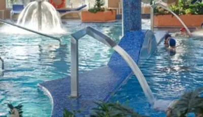 a swimming pool with water fountains and people in it at Atico Cuntis Thermae in Cuntis