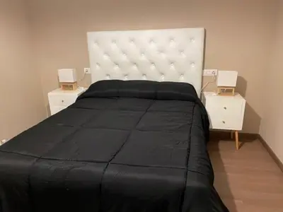 a bedroom with a large black bed and two night stands at Alojamientos con encanto Ruliña in Portomarin