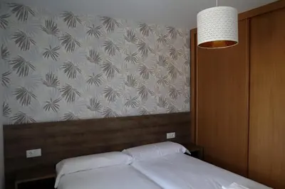 a bedroom with a white bed with a wall at Apartamento CATA Santiago de Compostela in Santiago de Compostela
