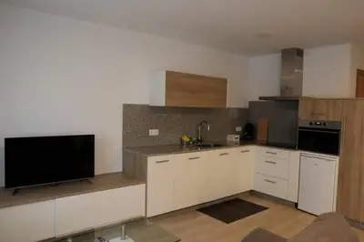 a kitchen with white cabinets and a flat screen tv at Apartamento CATA Santiago de Compostela in Santiago de Compostela