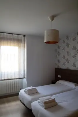 a bedroom with two beds and a window with towels on them at Apartamento CATA Santiago de Compostela in Santiago de Compostela