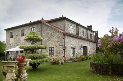 a large stone house with a yard with flowers at Casa De Cacheiro in Silleda